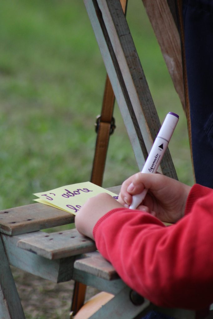 Un enfant écrit son souvenir d'arbre sur une feuille de papier. Dans le spectacle autour d'un arbre De souvenirs en racines.