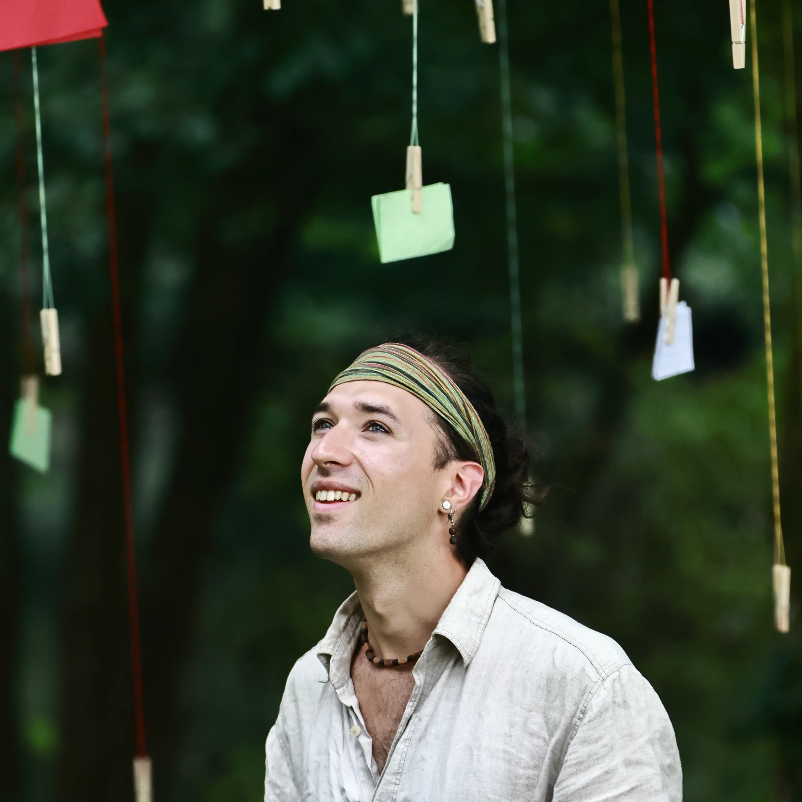 Un acteur Un homme souriant accroche des notes, illustrant l'harmonie entre nature et art au cœur d'un spectacle immersif De souvenirs en racine, montrant l'harmonie de l'engagement écologique